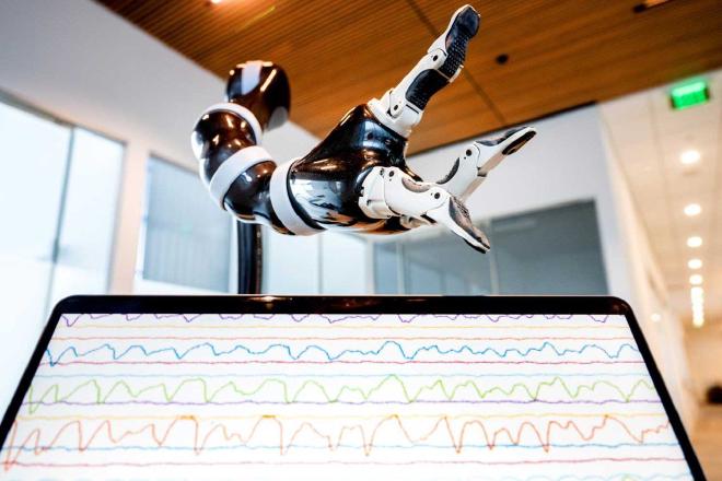 The robotic arm and the computer display with signals from interaction between the participant imaging movements ‘driving’ BCI interface. Image credit: Noah Berger