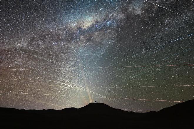 Esta imagen muestra satélites cruzando el cielo nocturno sobre el norte del desierto de Atacama en Chile, durante tan solo una hora. Se trata de una secuencia de imágenes grabadas a intervalos el 15 de octubre de 2025, aproximadamente dos horas después de la puesta del Sol. Algunas estelas son causadas por aviones, fácilmente identificables por sus luces de colores intermitentes, pero la mayoría corresponden a satélites. En primer plano vemos la cúpula del Telescopio Extremadamente Grande ( ELT ) del ESO, el telescopio óptico/infrarrojo más grande del mundo, actualmente en construcción en la cima del Cerro Armazones. Detrás, observamos los láseres del Telescopio Muy Grande ( VLT ) del ESO en el Observatorio Paranal, a 22 km del ELT. Crédito: F. Kamphues, ESO/M. Kornmesser