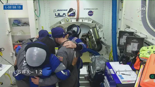 Behind, the access hatch to Starliner. In front, Williams and Wilmore pray with Boeing engineers and technicians. Image credit: NASA video screenshot